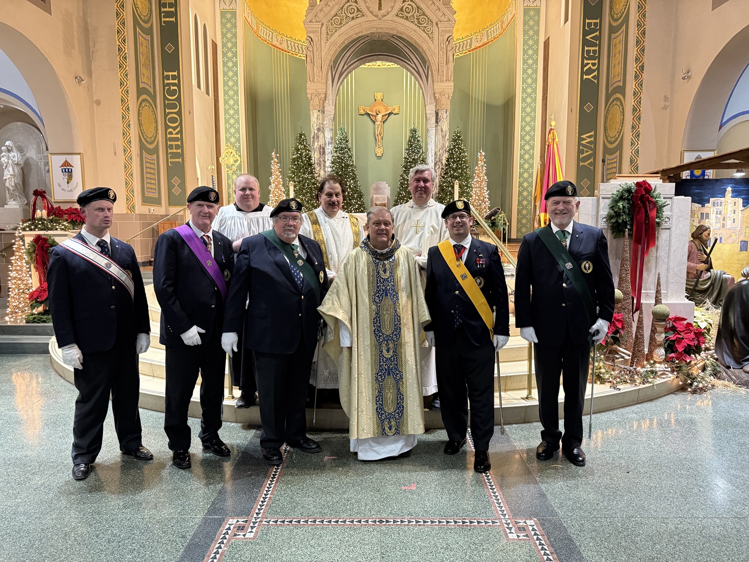A group in ceremonial uniforms and white vestments before a church altar.