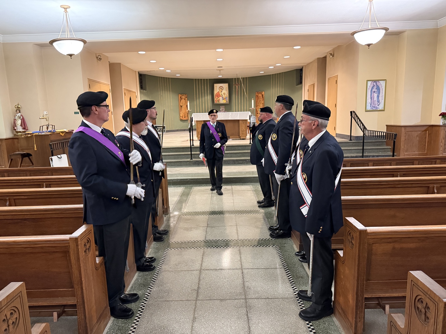 Uniformed participants holding ceremonial swords on both sides of a church aisle.