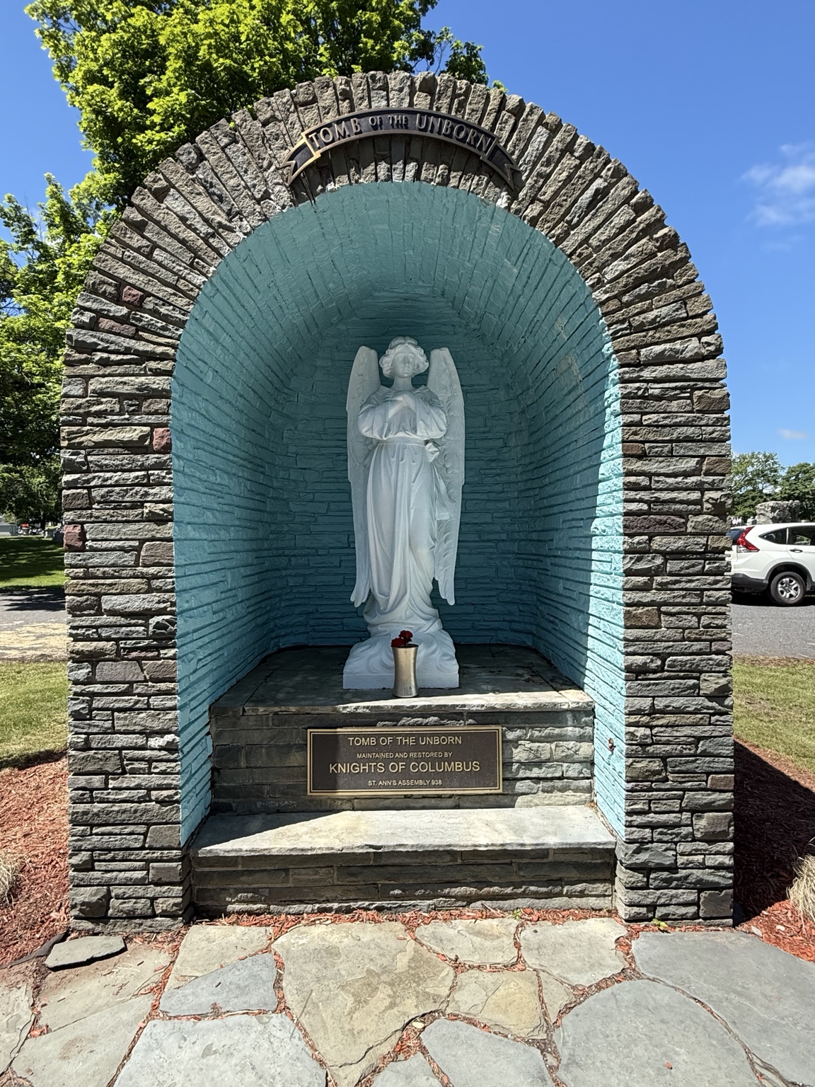 The restored Tomb of the Unborn with an angel statue and a plaque recognizing Saint Ann Assembly 938.